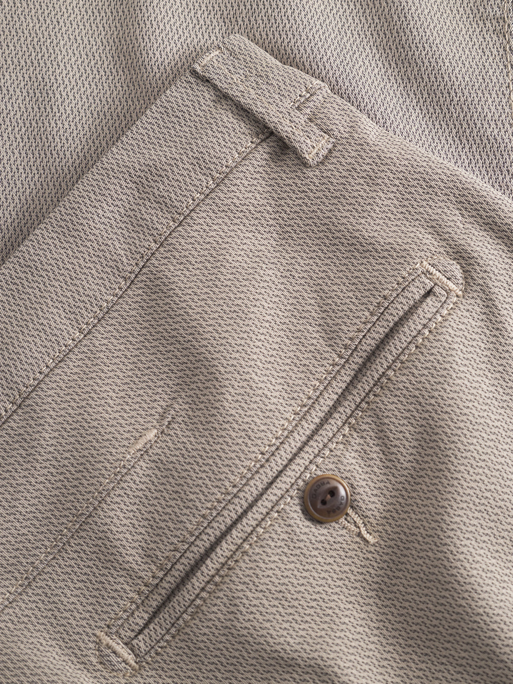 Close-up of GABBA GABpaul K3280 Dale Chino in Humus, showing beige textured fabric, back pocket with button, and belt loop, laid on a matching background.
