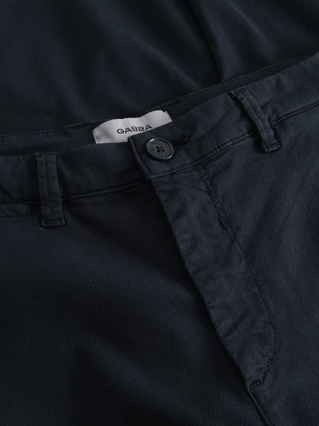 Close-up of Gabba GABpaul K3280 Dale Chino in Blue Black, featuring a slim fit, button and waistband detail, visible white Gabba label inside, and elegant French front pockets.