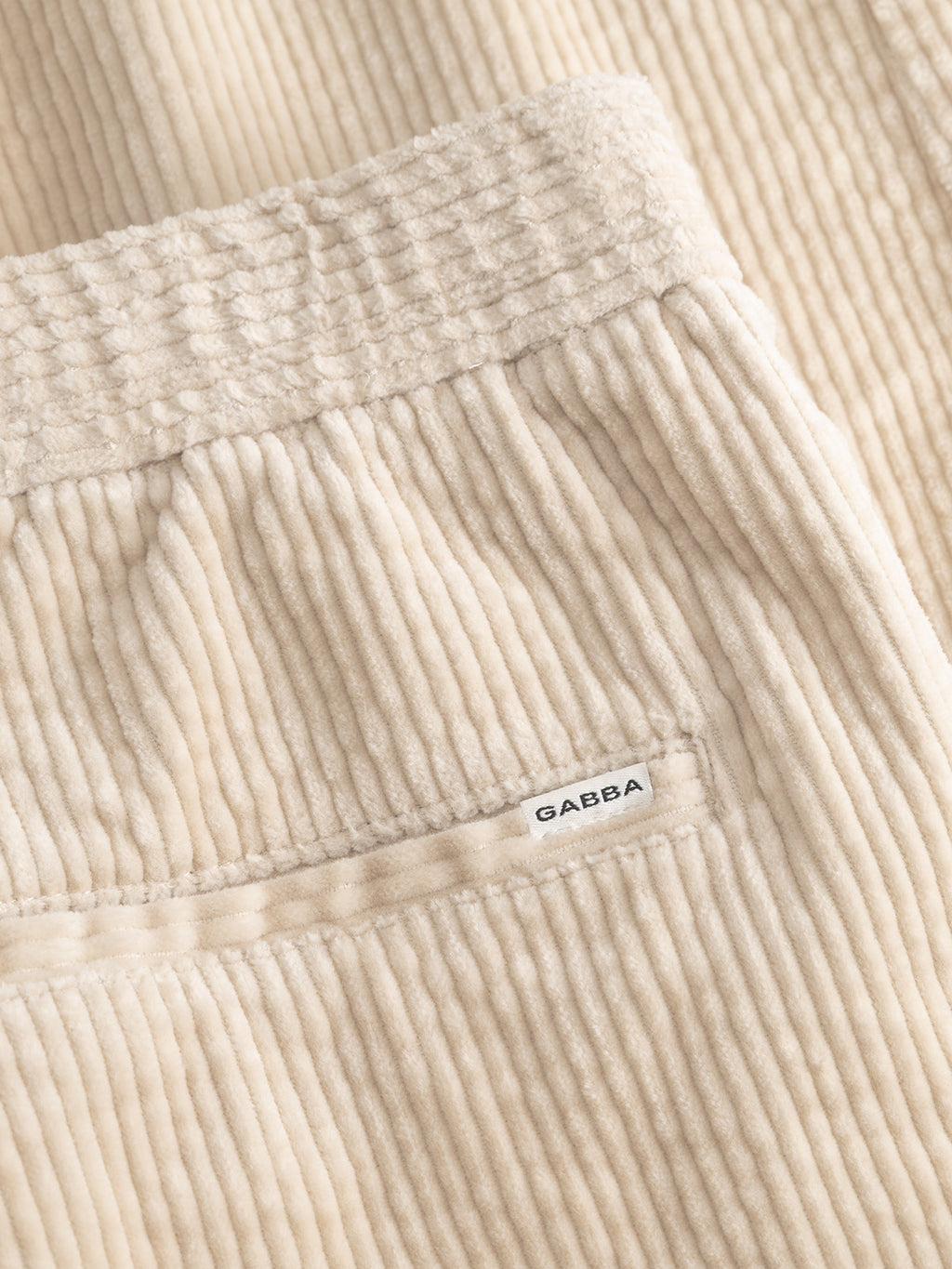 Close-up of the Gabba GABnapoli 19 Ibre Pant in Birch, crafted from premium beige cotton corduroy with visible ridges. The detailed view features a neatly constructed pocket and a small white label bearing the Gabba name, emphasizing the exceptional texture and tailoring of these men’s pants.
