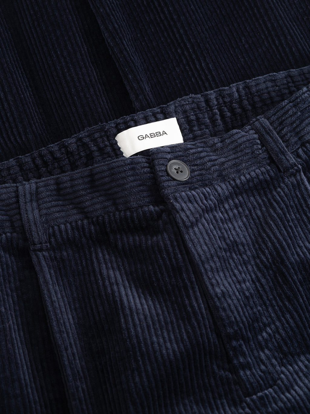 Close-up of GABnapoli 19 Ibre Pant - Dark Navy straight fit, dark navy cotton corduroy trousers featuring a button-fly closure and an interior waistband label.