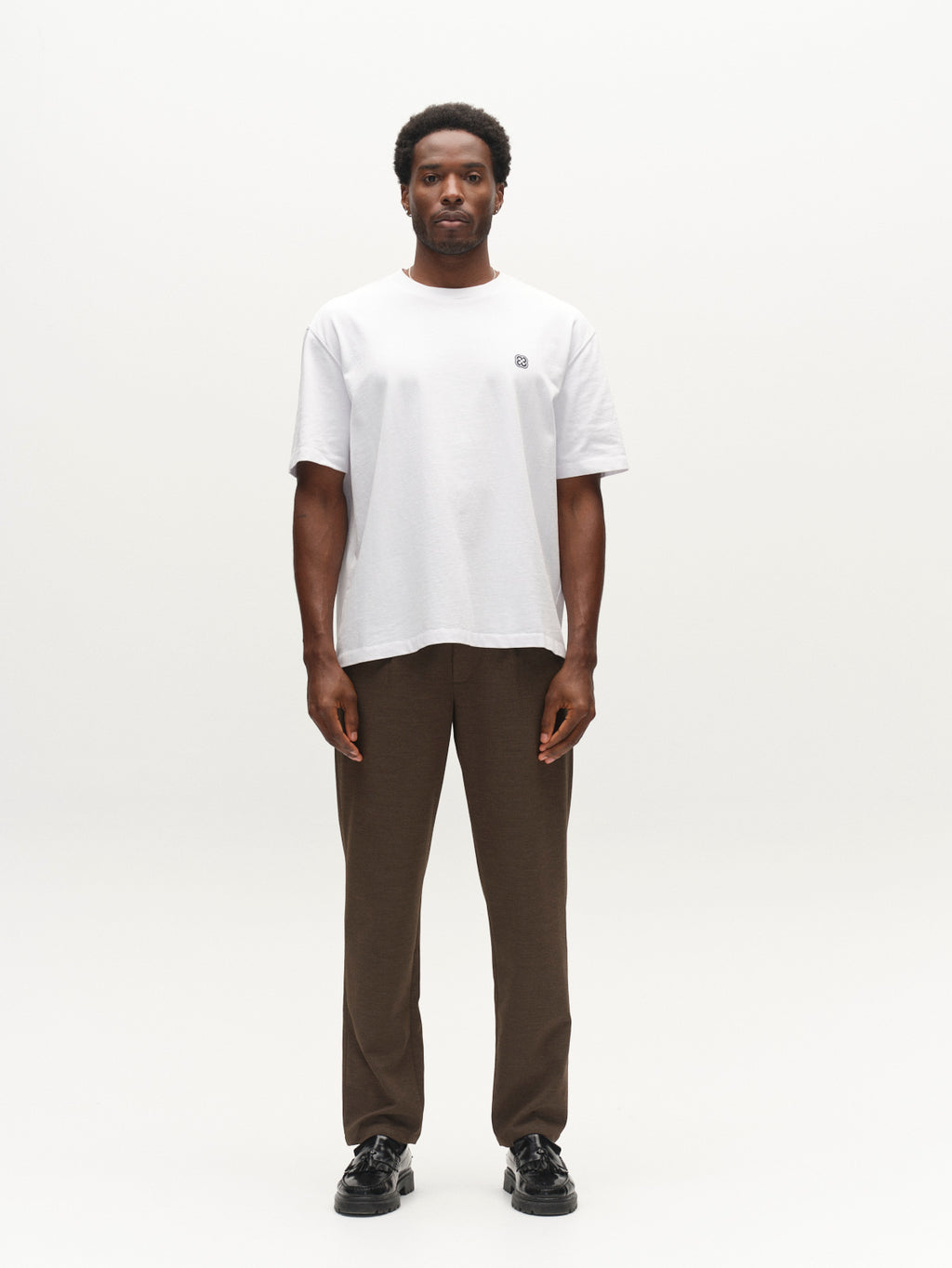 A man stands facing forward against a white background, wearing the Gabba GABnapoli 19 Phin GRS - Crocodile wool blend chino pants in a regular straight fit, paired with a plain white t-shirt and black shoes.