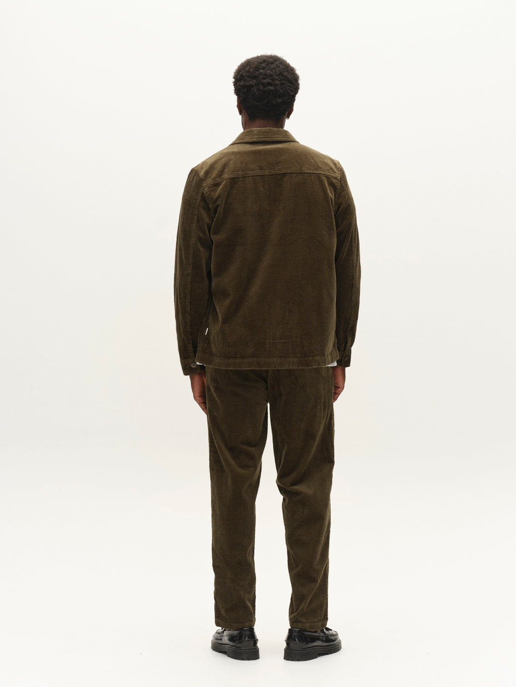 A person stands facing away from the camera, wearing the Gabba GABbeta Ibre LS Overshirt in Forest Night with coordinating pants and black shoes, set against a plain white background.