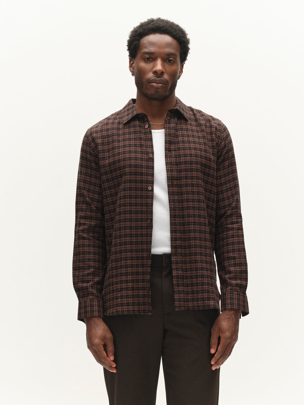 A man stands facing forward against a plain white background, wearing the Gabba GABsven Reg TX2 LS Shirt in Brown Slate—a regular-fit, checked-texture shirt—layered over a white undershirt and paired with dark pants.