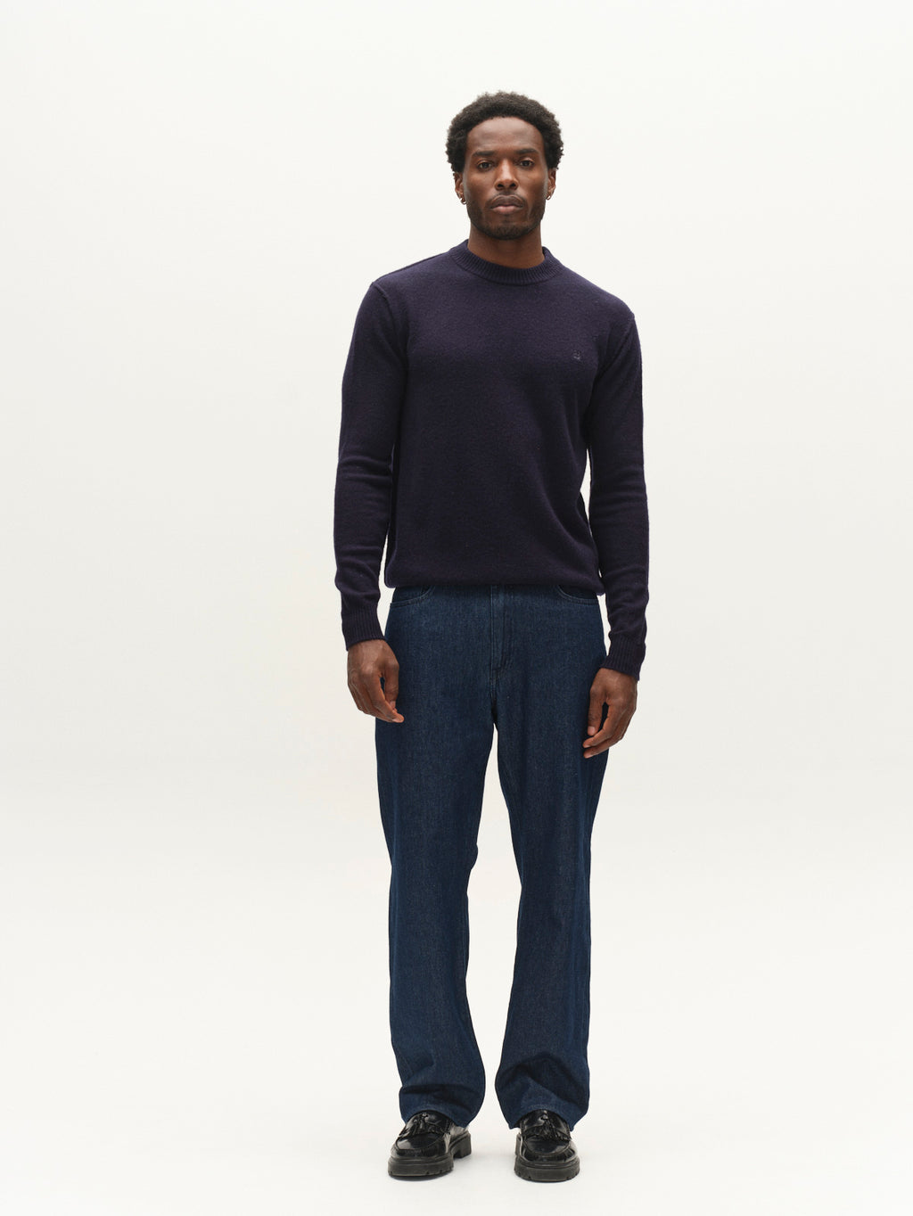 A man stands facing forward, wearing the Gabba GABtokota Element Aico LS Knit sweater in navy—a soft wool crew neck designed for everyday comfort—paired with blue jeans and black shoes, against a plain white background.