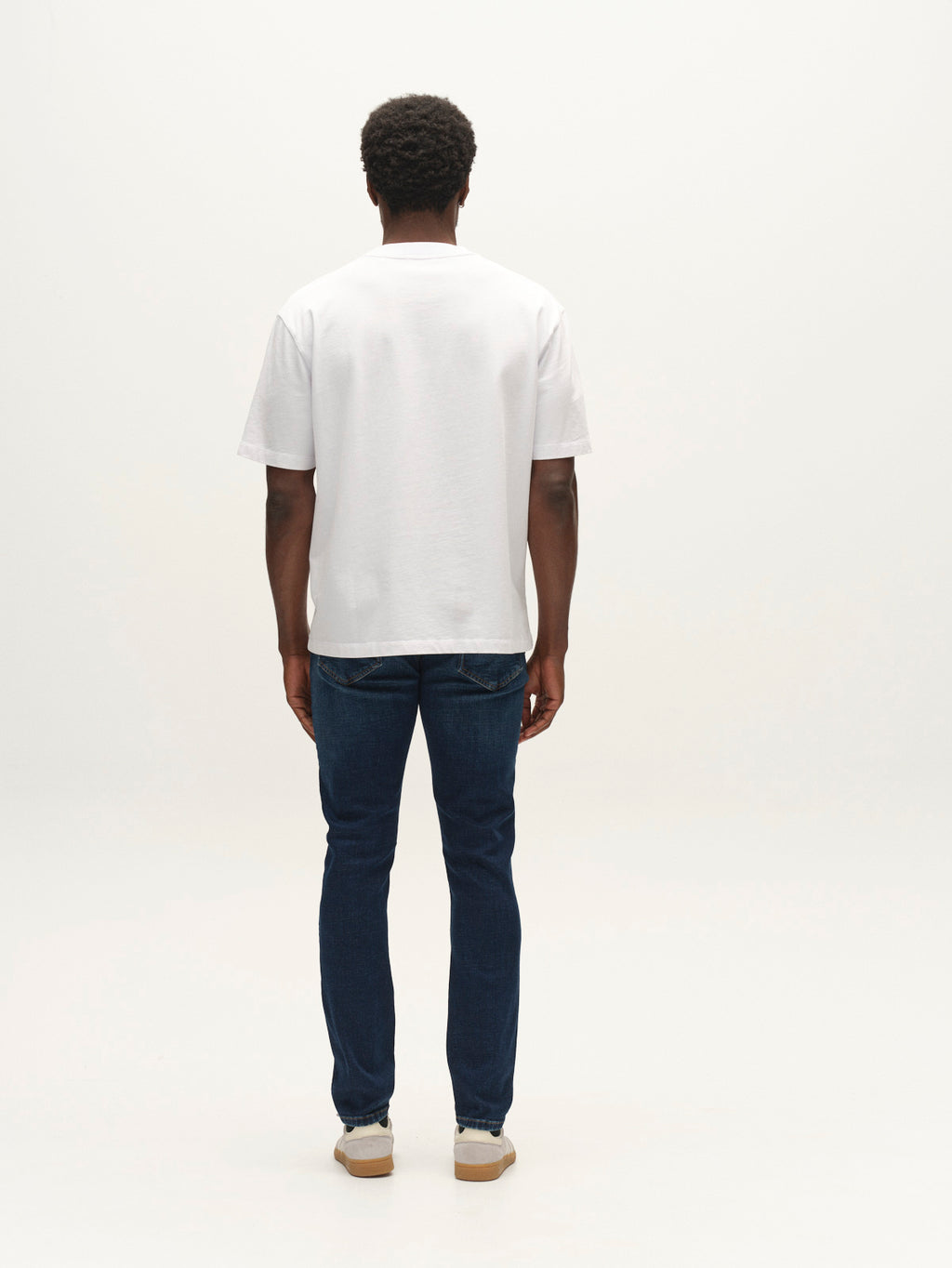 A person stands facing away from the camera, wearing a plain white T-shirt, sneakers, and Gabba GABjones Bekham DS0002 Jeans in dark blue denim crafted from comfort stretch fabric, against a white background.