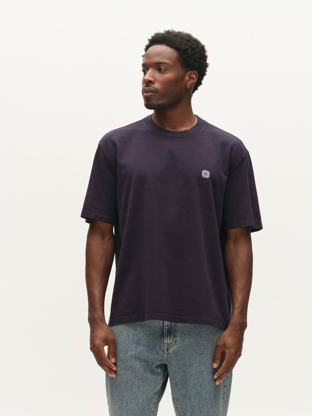 A man wearing the Gabba GABlegin Wix Boxy Hour Lobby2 SS T-shirt in Night Sky—a textured cotton jersey tee with a small circular chest logo—and light blue jeans stands against a plain white background, looking to his left.