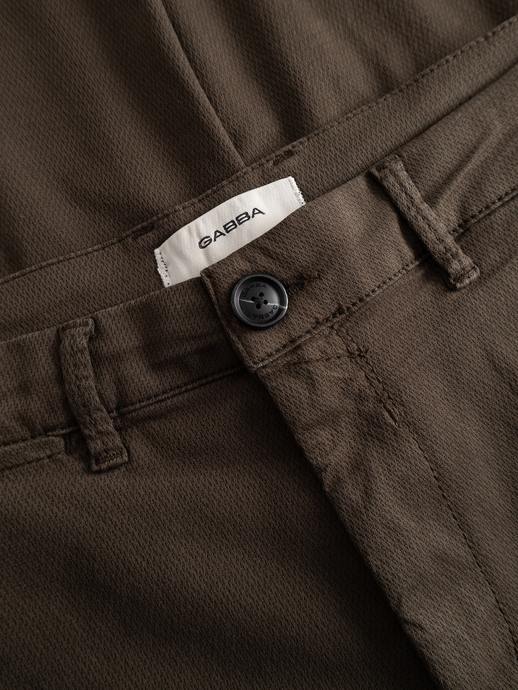 Close-up of the GABpaul K3280 Dale Chino in dark brown by Gabba, featuring French pockets, a black button, belt loops, and a white Gabba label on the waistband.