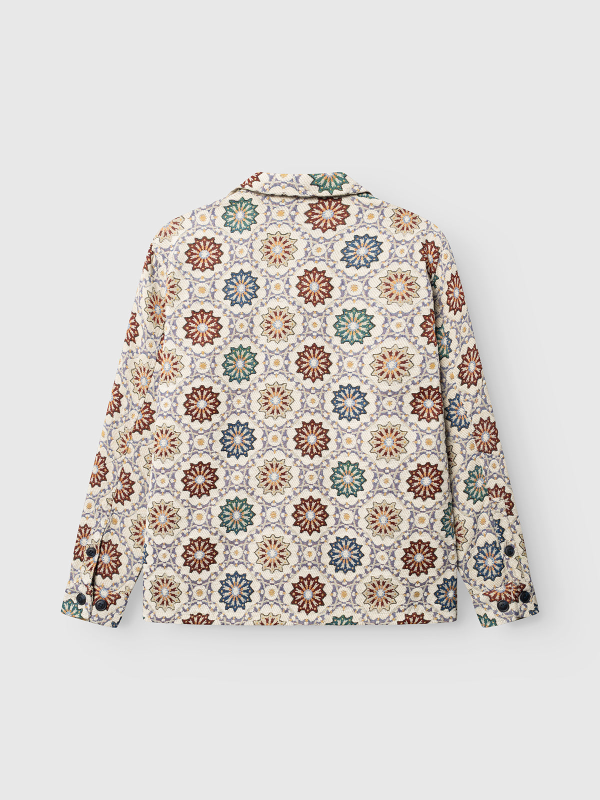 The Gabba GABsimone Nava LS - Birch is a long-sleeve shirt featuring a vibrant, repeating floral pattern in red, green, yellow, and blue on a white background. Shown from the back, it is designed with a relaxed fit for effortless comfort.