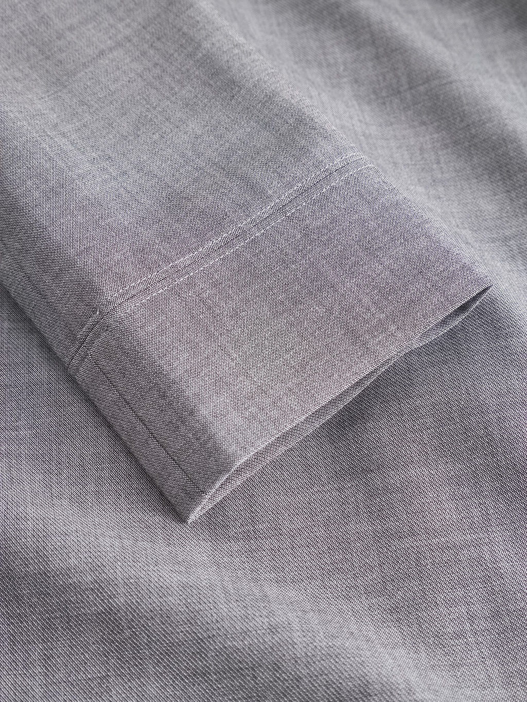 A close-up of the neatly folded sleeve of the Gabba GABnik Phin GRS - Dk. Grey shirt, crafted from a soft, finely woven wool and viscose blend fabric, highlights its detailed stitching and smooth texture.