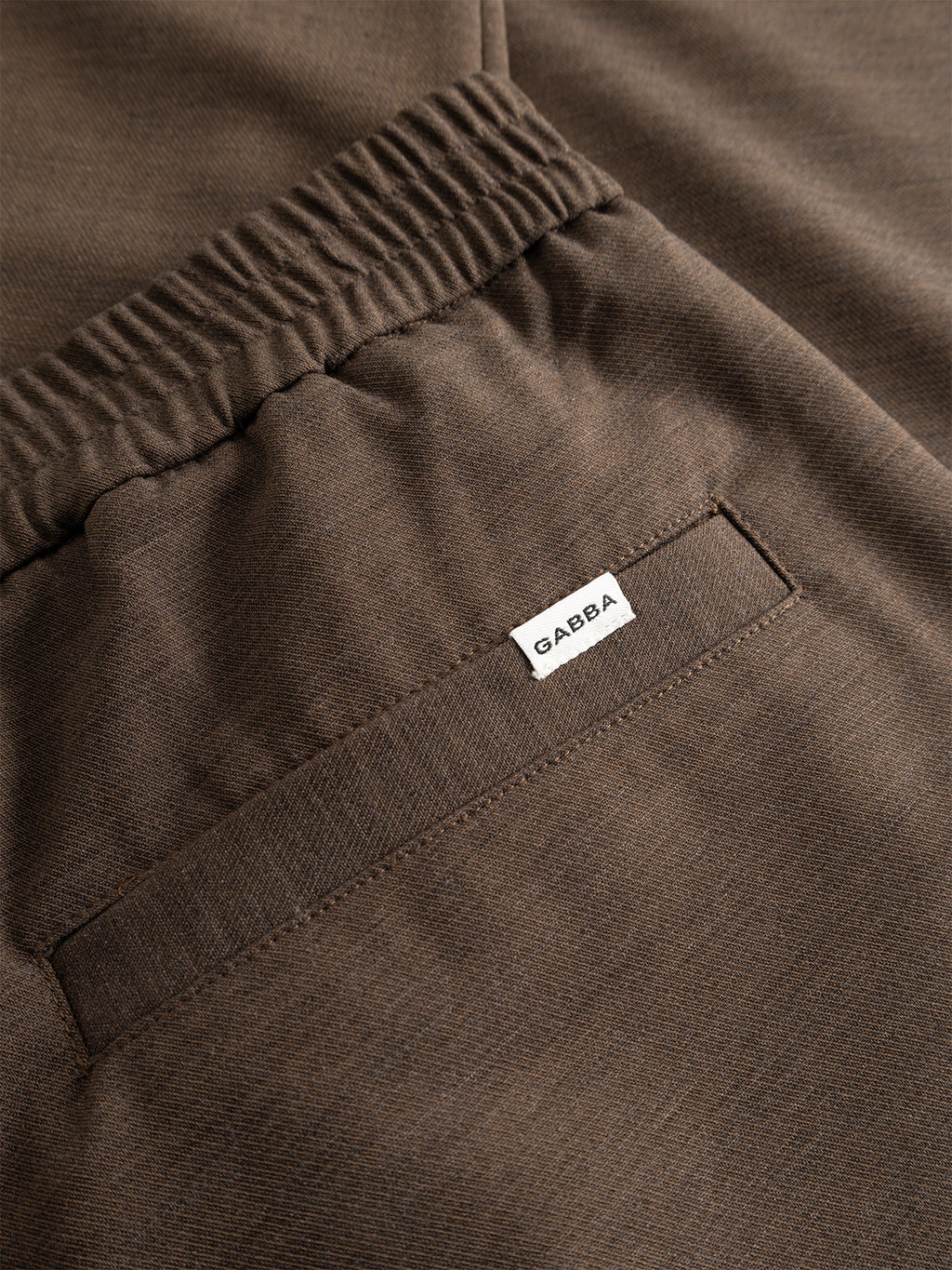 Close-up of the Gabba GABnapoli 19 Phin GRS - Crocodile chinos in a brown wool blend, featuring an elastic waistband and a back pocket detailed with a small white Gabba label. The fabric is soft, subtly textured, and made with recycled polyester for an eco-friendly appeal. Designed in a regular straight fit for both comfort and versatility.