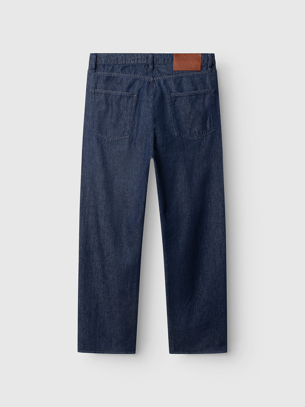 Back view of Gabba GABnoah Tona Rinse Jeans in dark blue denim, crafted from organic cotton indigo denim, featuring two rear pockets and a brown leather patch on the waistband, displayed against a plain light gray background.