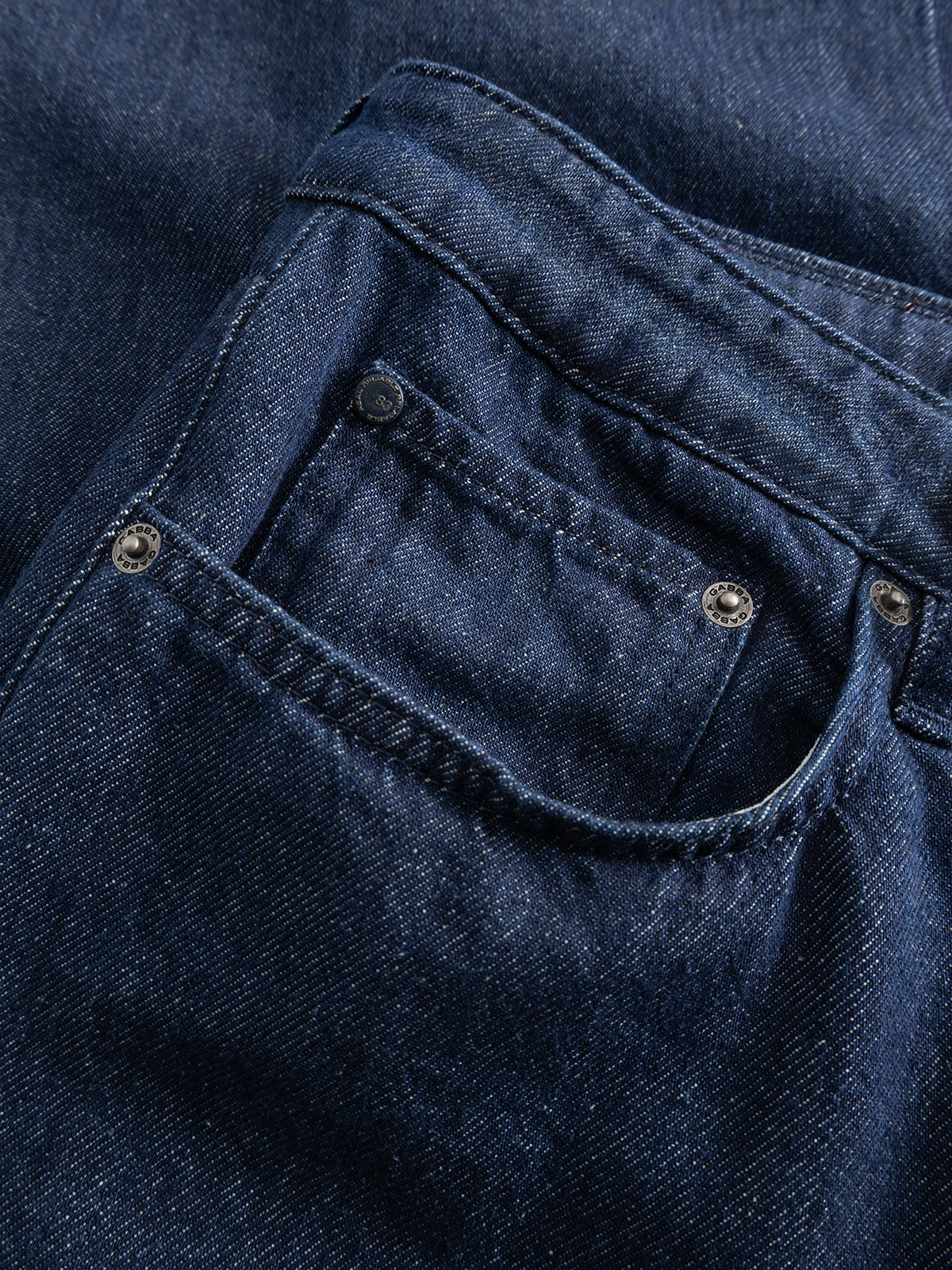 Close-up of the GABnoah Tona Rinse Jeans by Gabba in dark blue denim, highlighting the textured rigid indigo fabric, detailed stitching, and metal rivets.