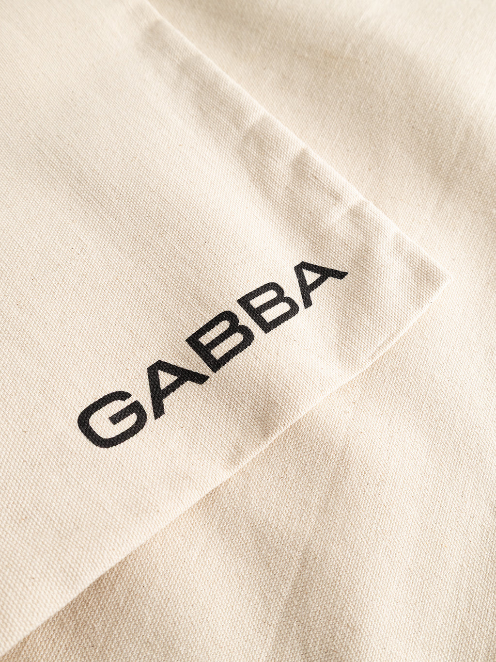 Off-white canvas GABworn Tote Bag featuring Gabba branding printed in black capital letters, perfect for everyday carry.