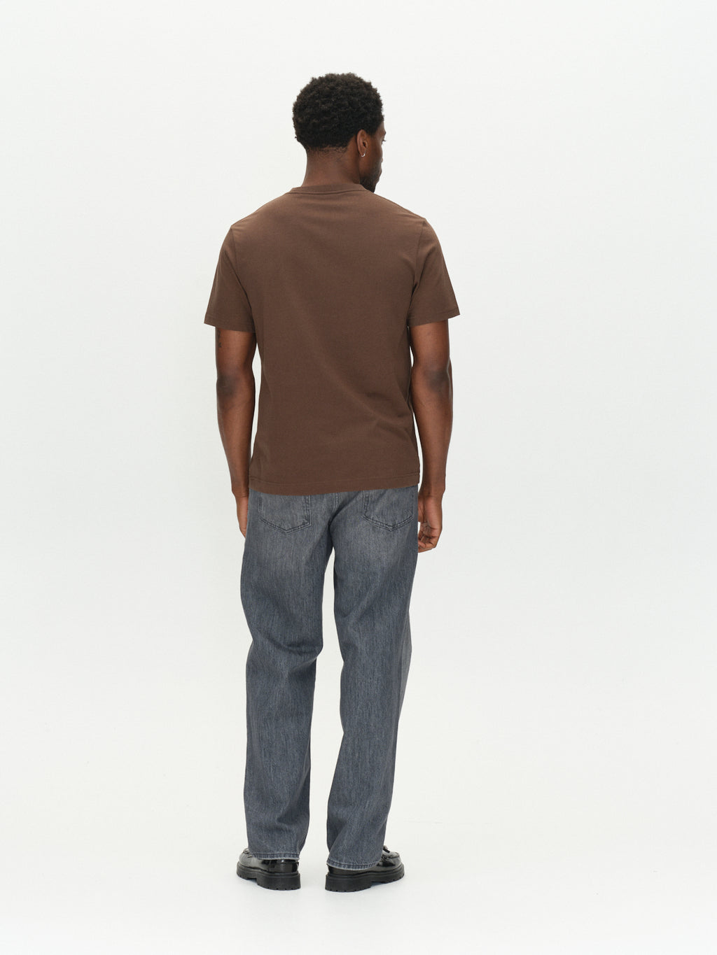 A man seen from behind wearing a brown slate GABdune Logo GOTS SS T-Shirt and grey jeans.