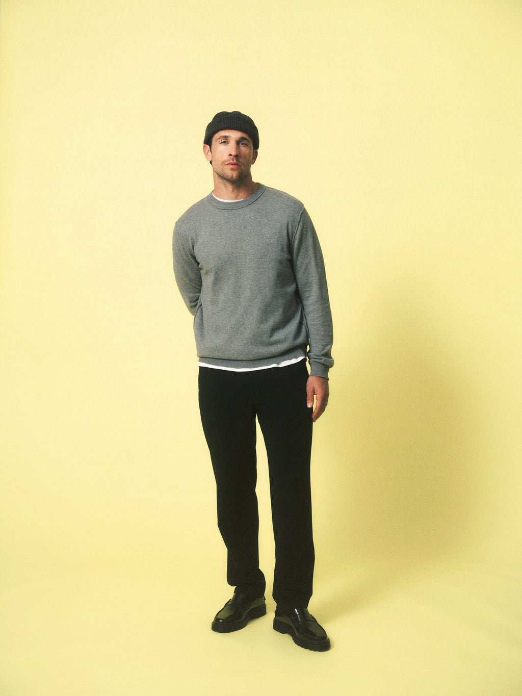 A man wearing Gabba GABnapoli 19 Phin GRS - Black pants stands against a plain light yellow background, looking at the camera with his hands behind his back.